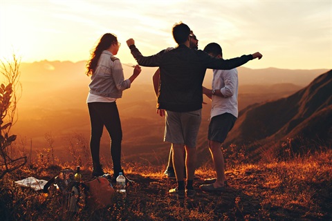 Young People standing on a hill with a sunset 