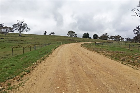 Looking uphill on an unsealed section of Abington Park Road in 2019 with hills and an overcast sky in the background.