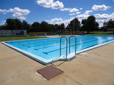 Photo from the corner of the main pool at Adaminaby, with an Australian Flag and trees in the background.