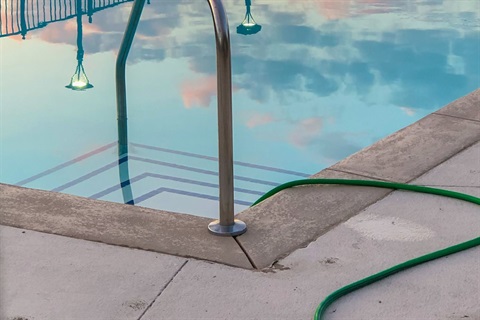 Close-cropped photo of garden hose filling a backyard pool