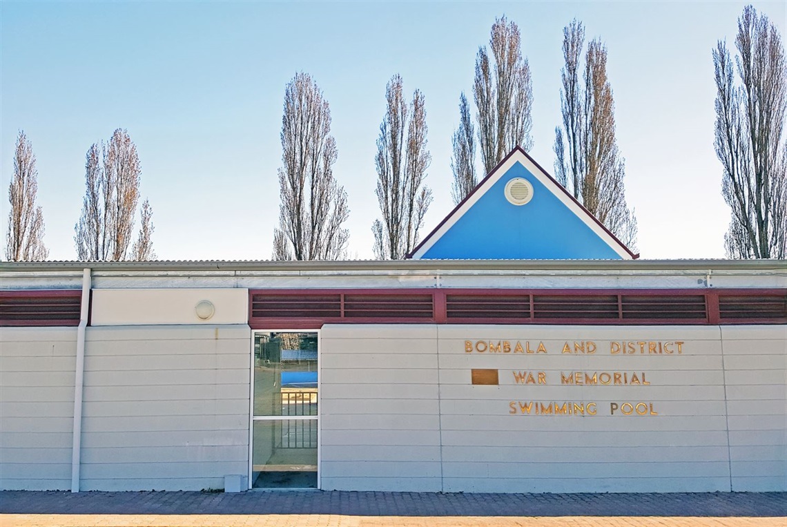 Exterior entrance of Bombala Pool, with blue sky and leaveless poplar trees behind.