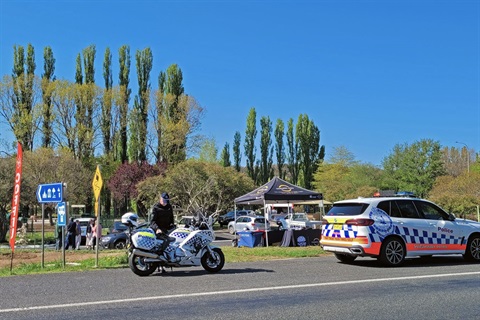 Police vehicles and an officer in the foreground of a roadside near Bombala with a coffee van and poplars in the background