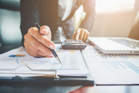 Man in suit reviewing hard copy financial documents