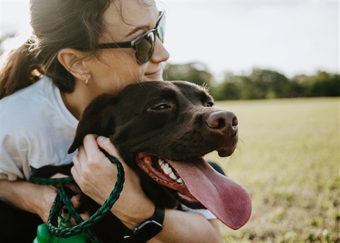 A woman hugging a dog in park